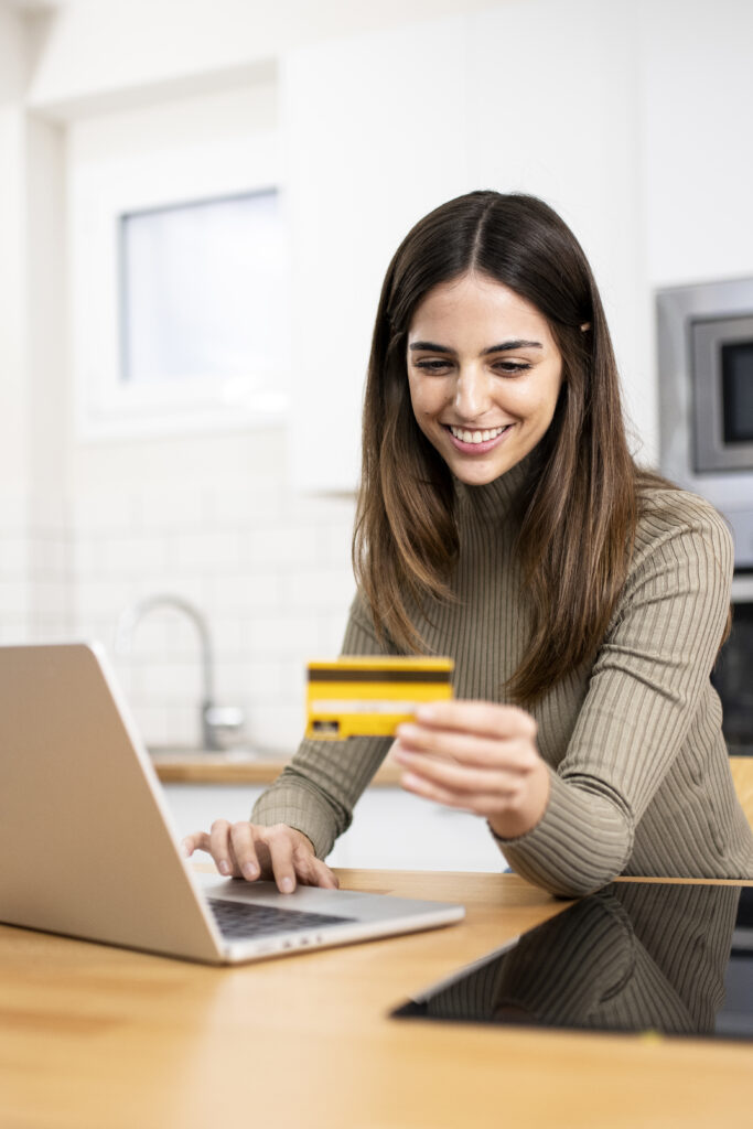 happy young attractive woman shopping online with a laptop computer using a credit card. e-commerce